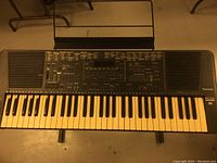 Top-down view of the Technics KN700 keyboard with sheet music stand mounted, showing keys, control panel, and built-in speakers.