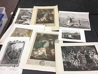 Eight unframed art pieces including black and white and colored prints depicting classical and historical scenes with human figures and animals, laid flat on table