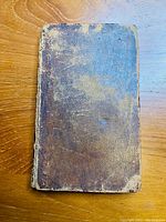 Front cover of the antique book showing worn brown leather with scuff marks and discoloration.