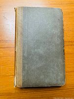 Front cover of the 1836 edition of 'Table Talk' by Samuel Taylor Coleridge showing grey textured cardboard cover with brown cloth spine, worn edges and loose binding.