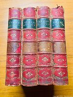 Four volumes of Samuel Pepys' Diary with red leather spines, black title labels, and gold embossing, showing signs of wear and a loose cover on volume one.