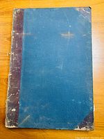 Top view of front cover of bound volume showing worn blue cloth covers with leather spine and corner reinforcements. Cover wear and discoloration visible.