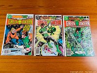 Photo showing three Green Lantern comic books (issues #162, #163, #164) laid out on a wooden surface.