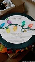 Close-up photo of the Wondershop multicolor faceted LED C9 lights plastic reel with label showing key features including 80 bulbs, 79 feet lit length, indoor/outdoor use, and Philips LED bulbs.