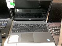Front view showing the full keyboard, touchpad, and part of the screen reflecting surroundings with moderate glare and fingerprints.