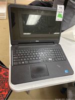 Open Dell laptop on white table showing screen and keyboard with numeric keypad.