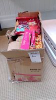 Photo showing the damaged box containing multiple Our Generation doll clothing packages.