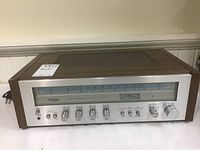 Front angle view of the Technics stereo receiver showing wooden side panels, power cord, and the main tuning dial.