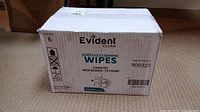 Front view of sealed white box of Evident Clean surface cleaning wipes showing brand name, product type, and quantity.