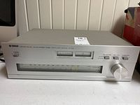 Front view of silver Yamaha CT-510 stereo tuner showing signal meters, frequency dial, buttons, and tuning knob.