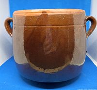 Front view of glazed ceramic bean pot showing brown and tan glaze with two side handles.