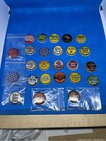 Photo showing a collection of 25 vintage bottle caps, mostly cork backed, arranged on blue background with some in plastic bags.