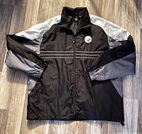 Front view of the black, gray and white Reebok nylon jacket with Steelers patch.