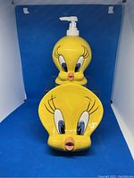 Photo of yellow ceramic Tweety Bird shaped soap dish and matching pump dispenser on blue background