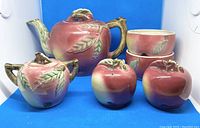 Photo of full vintage ceramic apple tea set showing teapot, sugar bowl, salt and pepper shakers, and two handleless cups