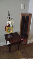 Photo depicting the antique wooden shutter, side table, and metal picture frame display stand arranged near a wall and switch plate.