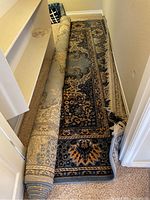 Rolled rug in narrow hallway showing border and pile.