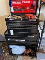 Front view of stacked upper chest and lower cabinet on casters, partially filled drawers