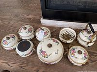 Full view of the enameled cookware pieces laid out, showing the floral designs, variety of pots, kettle, and Sterno warmer base.