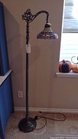 Full view of Victorian style floor lamp with Tiffany style stained glass shade in pink, white, green, and purple, showing height and design.