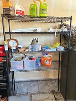 Black wire storage rack with multiple items on shelves in a garage setting. The rack is empty for sale as contents are not included.