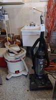 Two vacuums side by side: Dirt Devil upright vacuum in green and black, and Craftsman wet-dry vacuum in white with hose and wheels.