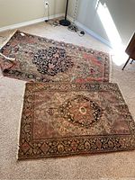 Both rugs laid flat on carpeted floor with surrounding floor lamps and wall outlet