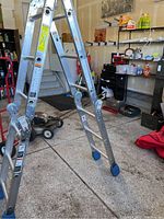 Image of the ladder set up in a garage showing the hinges and blue rubber feet on the legs for grip.