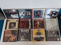 Photo of 12 blues music CDs arranged in two rows, showing cover art featuring various legendary blues artists.
