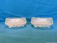 Two crystal glass bowls shown side by side against a blue background showing texture and shape of bowls.