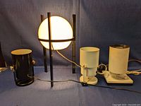 Front view of four lamps including one orb lamp with frosted glass and three cylindrical spotlight lamps.