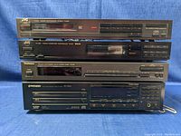 Stacked stereo components including JVC TGX2 and FX-330 tuners, Technics ST-K50 tuner, and Pioneer PD-T505 CD player on bottom