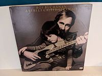Roy Buchanan album cover featuring a man holding a child and both holding an electric guitar on a brown background.