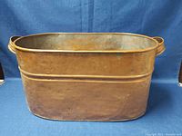 Front and side view of the oval copper wash tub showing aged patina and handle details.