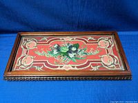 Top-down photo showing entire rectangular wooden tray with glass top and embroidered floral design beneath the glass.