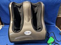 Front view of Dr. Ho massager showing dual foot slots with black fabric interiors and brown plastic exterior.