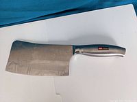 Full view of heavy-duty bone cleaver with taped sharp blade and ergonomic stainless steel handle