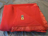 Red Kenwood wool blanket folded showing satin trim and label.