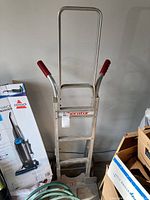 Full view of the Liberator hand truck showing the metal frame and red handles.