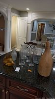 Overview of all vases displayed on dark granite countertop under kitchen lighting, showing variety of shapes and materials.