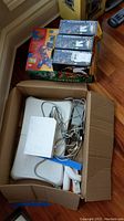Box containing Nintendo Wii accessories including Balance Board, sensor bar, cables, and Wii console.