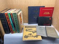 Photo showing the full lot of automotive books and manuals, arranged on shelf with some standing and some lying flat.
