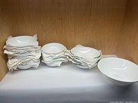 Grouped stacks of white bowls in different sizes and styles, with a single large white bowl separate on the right