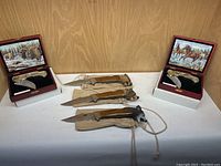 Lot arrangement with three fixed blade animal-head handle knives and two folding knives in display boxes with wildlife artwork