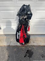 Front view of complete Cleveland-branded black golf bag with multiple clubs inside and red towel hanging off the side.