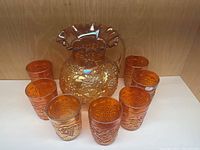 Full set showing one Imperial Carnival Glass pitcher and seven matching glasses arranged around it.