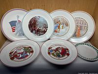 Display of 11 Corelle decorative plates with various holiday and patriotic designs including Statue of Liberty, winter scenes, and Christmas Santa Claus.