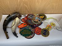 Lot showing three powder horns and a pile of colorful hunting patches and pins.