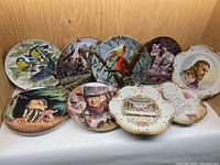 All nine decorative collector plates arranged showing their detailed paintings and designs