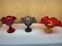 Front view of all three fluted vintage glass bowls on display showing their ruffled edges and pedestal bases.
